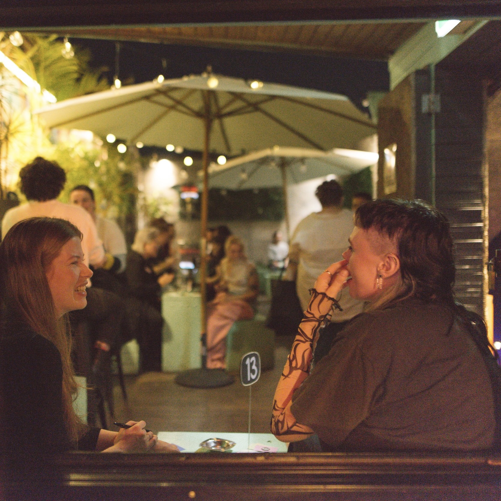 two people on a date with brown hair laughing and sitting at a table with a number on it